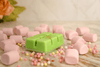Handcrafted green wax melts surrounded by colorful candies, evoking childhood joy, sweet scents, and cozy moments at home.