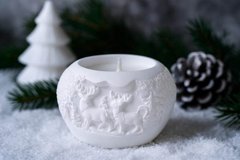 White ceramic candle holder with animal designs on a snowy background
