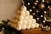 Decorative candle shaped like a pyramid with gold accents on a wooden base against a festive background.