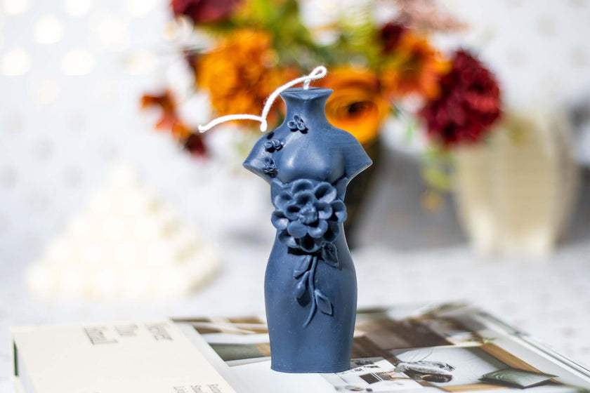 Elegant sculptural candle resembling a dress with floral details, perfect for home decor.