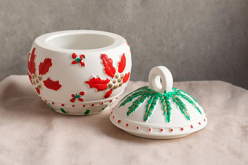 Decorative ceramic pot with red floral design and matching lid on a neutral background