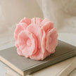 Pink flower-shaped candle on a stack of books with a soft beige background