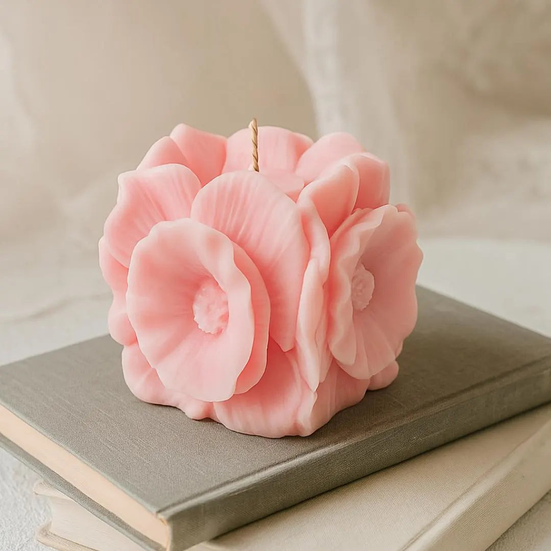 Pink flower-shaped candle on a stack of books with a soft beige background