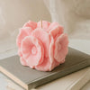 Pink flower-shaped candle on a stack of books with a soft beige background