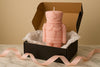 Pink nutcracker-shaped candle in a black box with tissue paper on a beige background