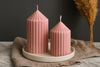 Two pink ribbed candles on a white plate with a dark background