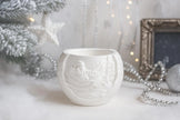 White ceramic mug with embossed design on a white surface with decorative elements.