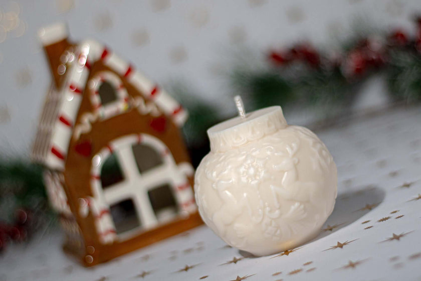 Handmade Christmas Globe Reindeer scented candle by a festive gingerbread house, perfect for holiday ambiance.