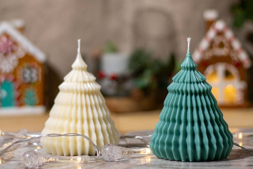 Decorative scented candles shaped like Christmas trees in cream and teal, enhancing festive holiday decor.