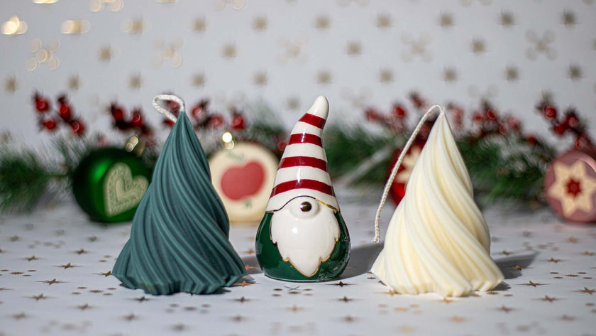 Three decorative gnome-shaped candles in green, white, and red, perfect for festive holiday decor.