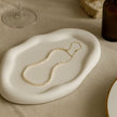 Gold necklace on a white ceramic dish with a neutral background
