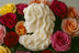 Intricately carved Medusa bust candle in ivory wax, surrounded by vibrant roses for a dramatic and artistic home décor piece.