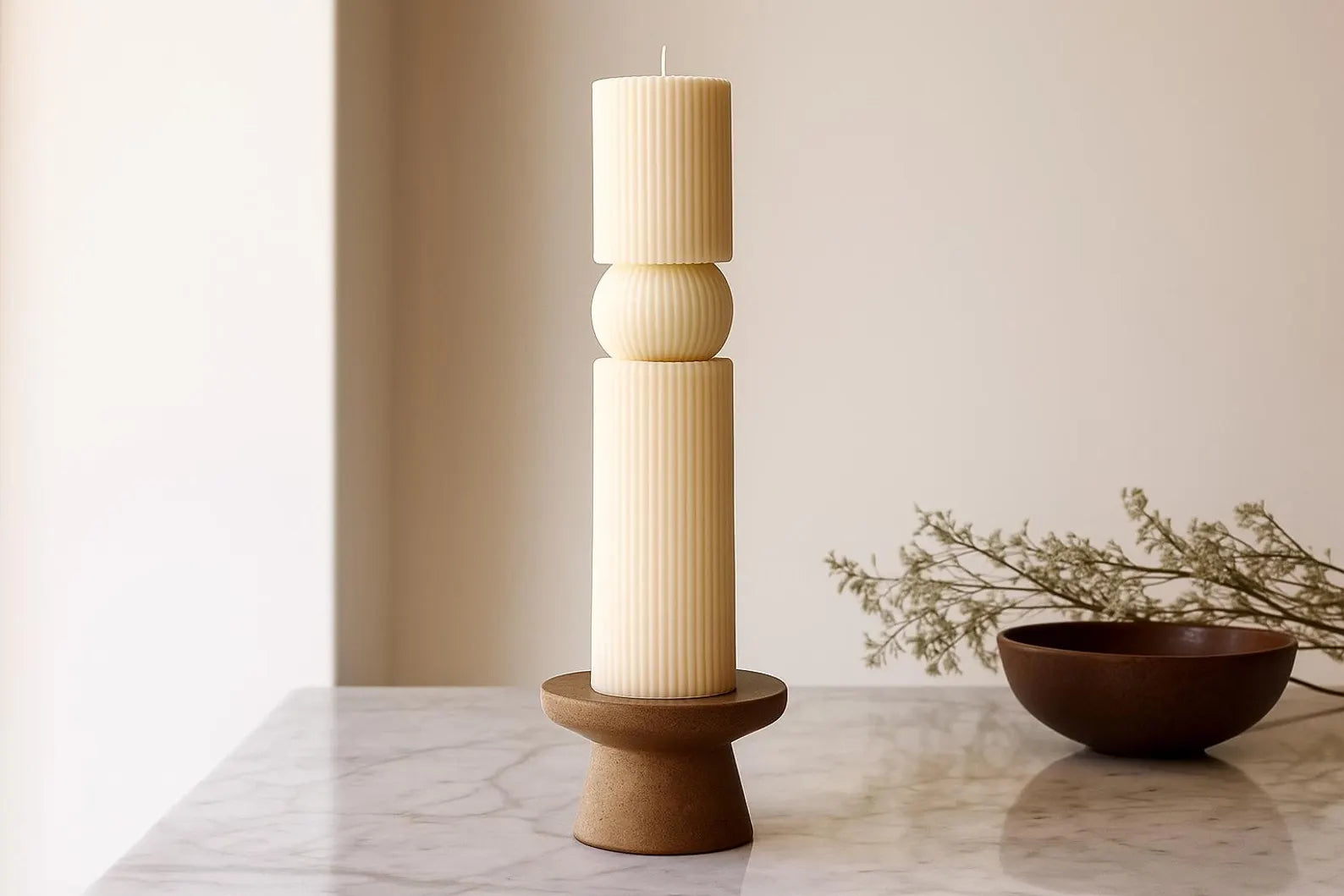Decorative candle in a wooden holder on a marble surface with a neutral background