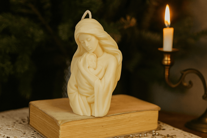 Candle-shaped sculpture of a woman holding a child on a book with a lit candle in the background.