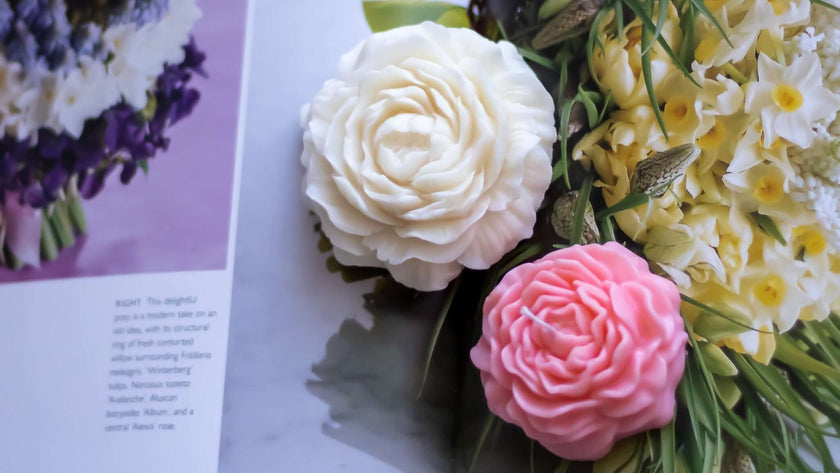 Close-up of handmade sculptural soy wax candles shaped like rose blossoms in white and pink.