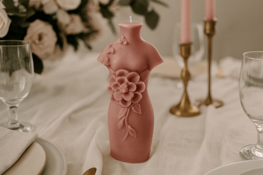 Pink floral candle on a table setting with glasses and candles in the background
