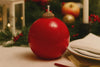 Red ball-shaped candle on a table with Christmas decorations in the background