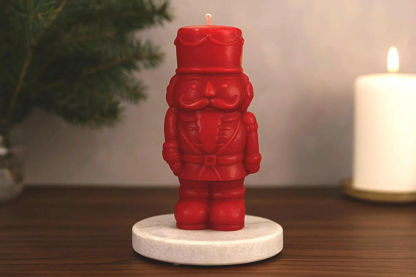 Red nutcracker-shaped candle on a wooden surface with a blurred background