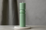 Green candle holder with a candle on a gray surface and background