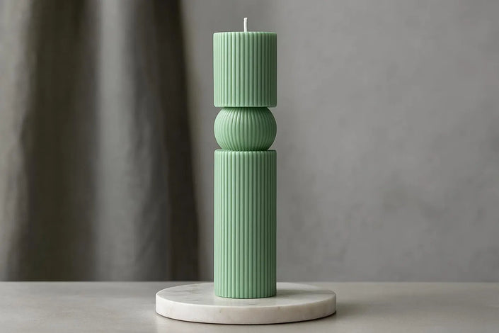 Green candle holder with a candle on a gray surface and background