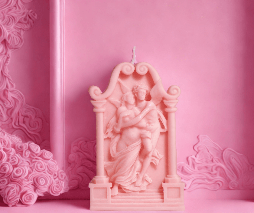 Decorative pink soy wax sculpture of a couple embracing, set against a pink backdrop.