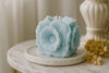 Blue flower-shaped candle on a marble surface with a blurred background