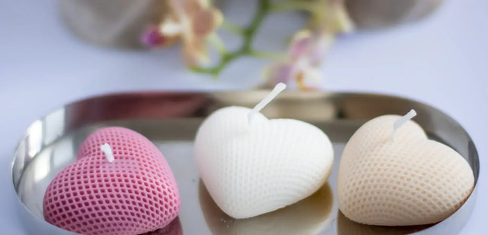 Sculptural heart soy candles in pink and ivory tones, placed on a silver tray