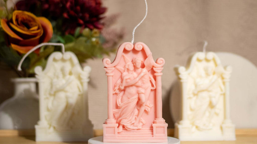 Pink decorative soy wax sculpture of lovers with white sculptures in the background, ideal for romantic decor.
