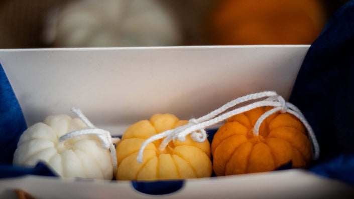 Close-up of a decorative mini pumpkin candle, showcasing its detailed design and eco-friendly soy wax composition.