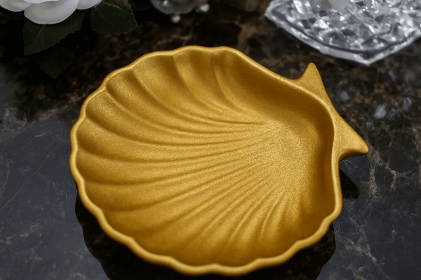 Gold shell-shaped dish on a dark surface