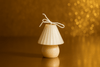 Small white mushroom candle on a reflective surface with a warm, blurred background