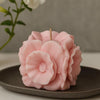 Pink flower-shaped candle on a dark plate with a blurred floral background