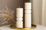 Decorative candle holder with candles on a round gold tray against a neutral background