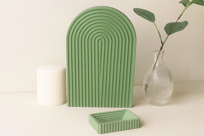 Green ceramic arch and rectangular planter on a light surface with a vase and candle in the background.