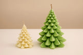 Two Christmas tree-shaped candles, one beige and one green, on a beige background.
