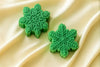 Two green snowflake candles on a beige fabric background