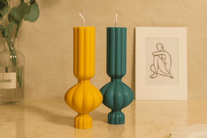 Two colorful candles in unique forms on a table with a minimal background
