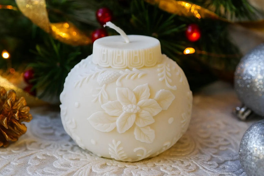 Decorative candle with floral patterns on a textured surface with Christmas decorations in the background