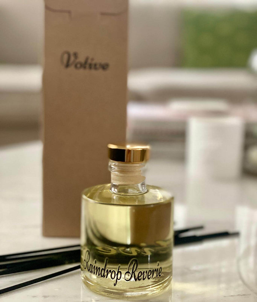 Premium transparent glass reed diffuser bottle with natural rattan reeds and fresh greenery

