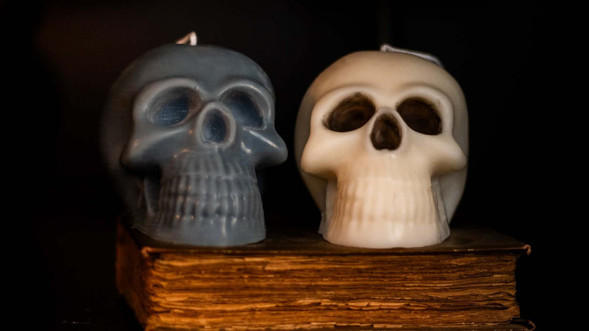 Gothic skull candles in gray and white displayed on an antique book, perfect for Halloween decor.