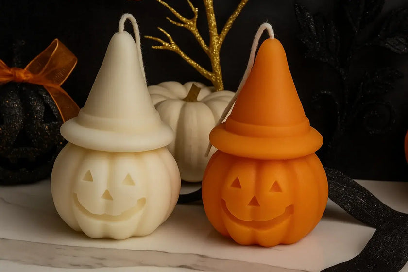 Two Halloween-themed candles, one white and one orange, with pumpkin shapes on a dark background.