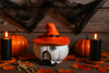 Halloween-themed decor with pumpkins, candles, and a witch hat on a wooden surface.