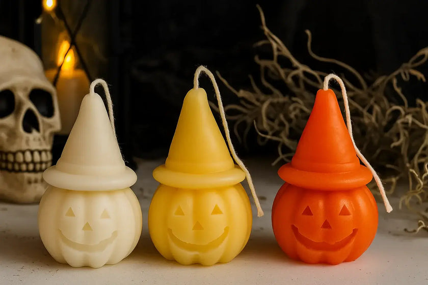 Three Halloween-themed candles shaped like jack-o'-lanterns on a dark background.