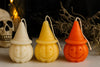 Three Halloween-themed candles shaped like jack-o'-lanterns on a dark background.