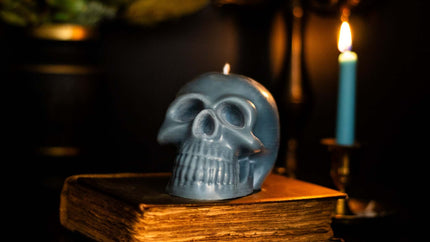 Scented Gothic Skull Candle in natural wax, perfect for Halloween decor, placed on an antique book with candlelight ambiance.