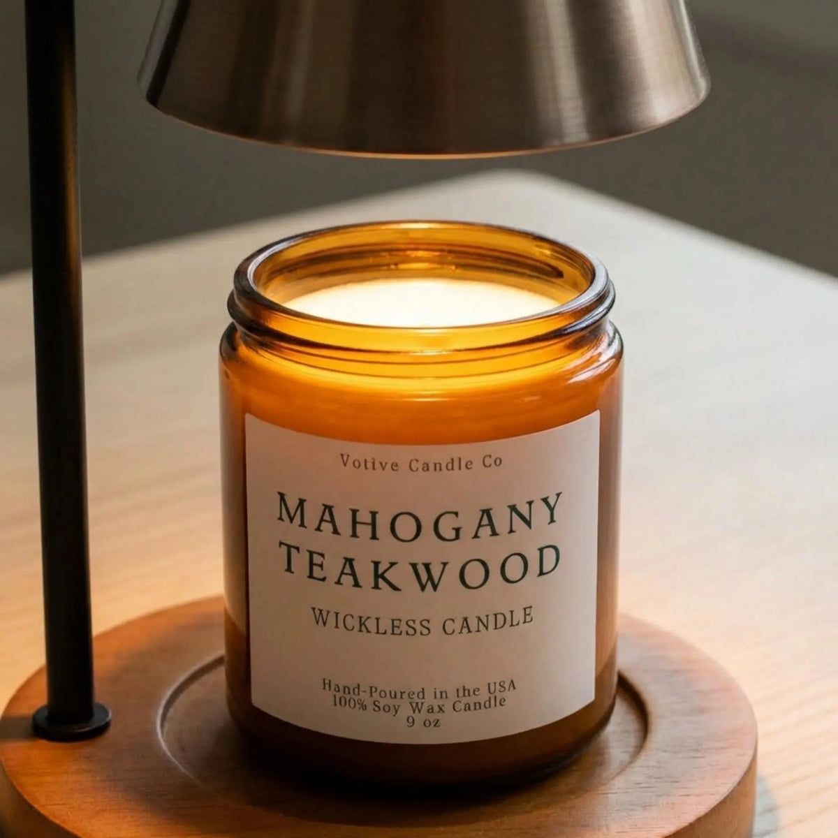 Votive Candle Co Mahogany Teakwood wickless candle on a wooden coaster with a lamp in the background