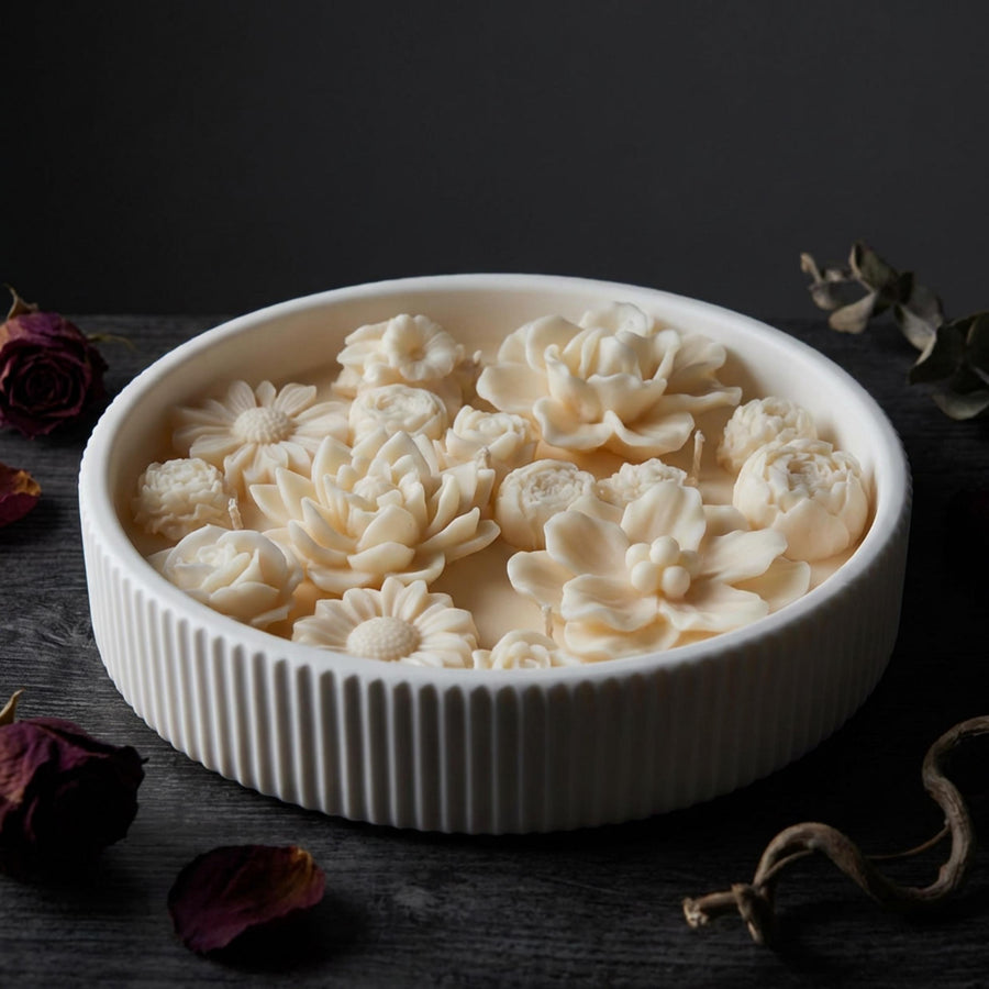 White ceramic botanical candle with floral designs on a dark surface by Votive Candle Co