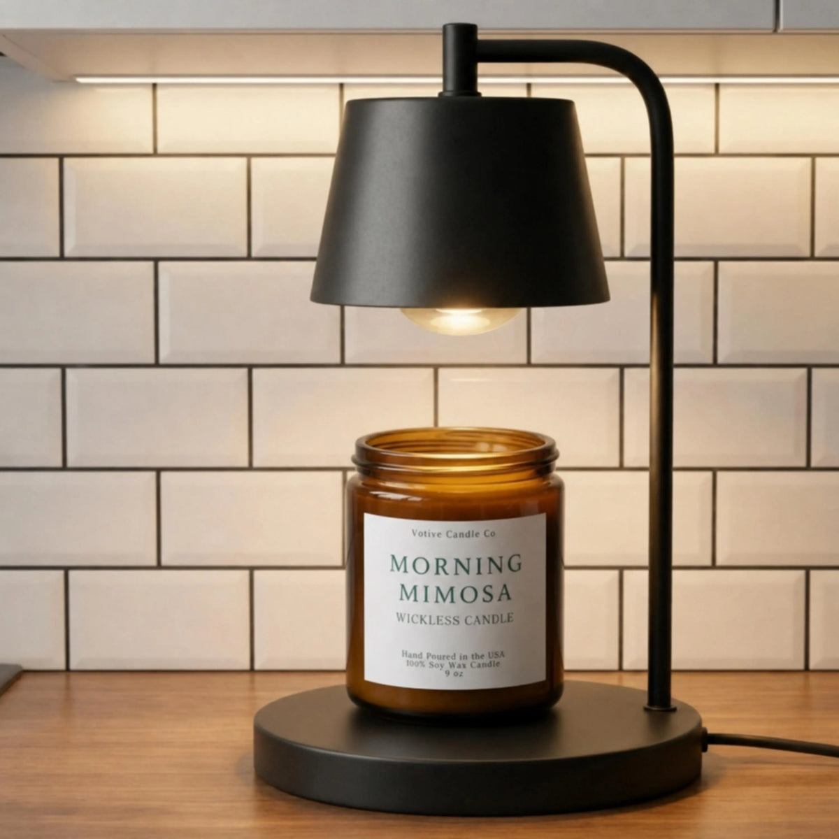 Amber jar wickless candle labeled 'Morning Mimosa' on a black lamp base with a tiled wall background