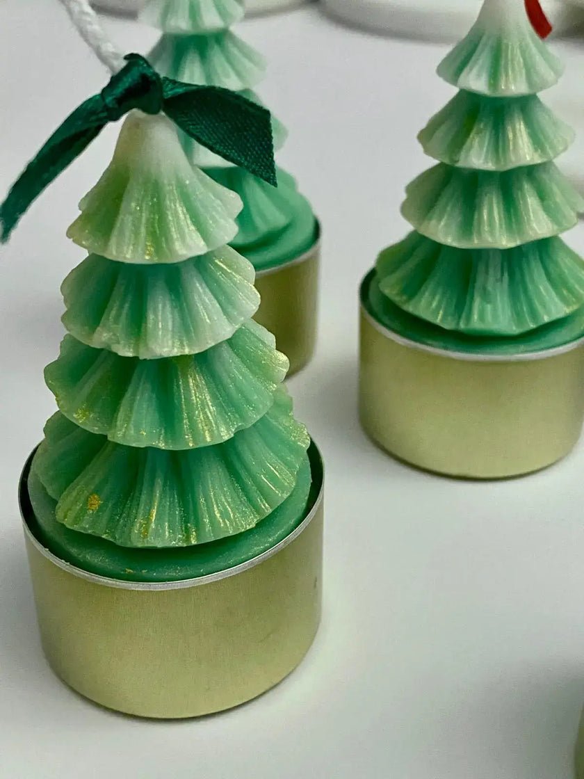 Decorative natural Christmas tealights shaped like pine trees in green and gold for festive ambiance.