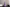 Purple textured candle on a black surface with a vase and books in the background